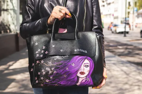 穿着黑色皮夹克的人提着黑色和紫色的皮包