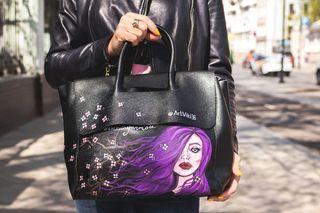 穿着黑色皮夹克的人提着黑色和紫色的皮包