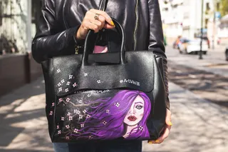 穿着黑色皮夹克的人提着黑色和紫色的皮包