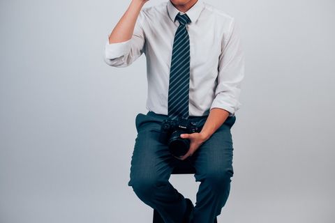 白色礼服衬衫和蓝色裤子拿着数码单反相机的男人