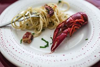 精美的晚餐，搭配海鲜意大利面、小龙虾和红酒，餐桌上装饰着玫瑰