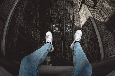 穿着蓝色粗斜纹棉布水洗合身牛仔裤和白色低帮运动鞋的人 穿着蓝色粗斜纹棉布水洗合身牛仔裤和白色低帮运动鞋的人