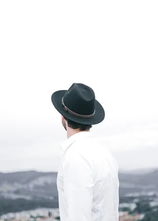 戴着黑色软呢帽的男子俯瞰群山