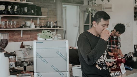 穿黑衬衫的男子从杯子里喝水