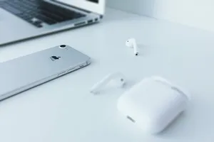 银色iPhone 7躺在苹果AirPods附近的白色表面上