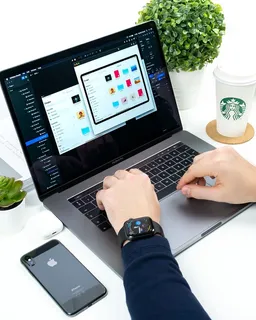 在星巴克杯和iPhone之间使用笔记本电脑的人 在星巴克杯和iPhone之间使用笔记本电脑的人