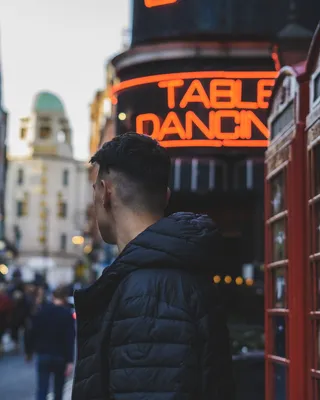 穿着黑色泡泡夹克的男子站在电话亭附近