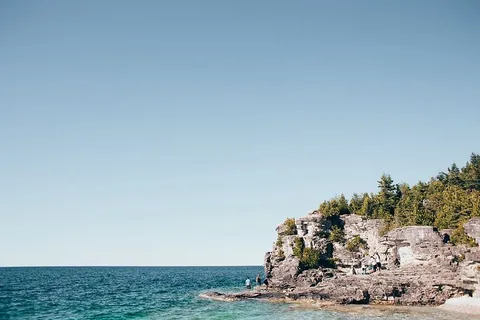 年轻的徒步旅行者在蓝绿色海洋海湾附近的岩石上 年轻的徒步旅行者在蓝绿色海洋海湾附近的岩石上