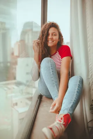 微笑的女人坐在窗台上的照片