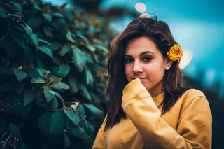 在选择性聚焦摄影的植物旁，身穿黄色毛衣的女人