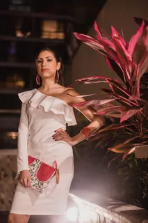 夜间,一名穿着白色连衣裙、拿着袋子的妇女站在植物旁边 夜间,一名穿着白色连衣裙、拿着袋子的妇女站在植物旁边