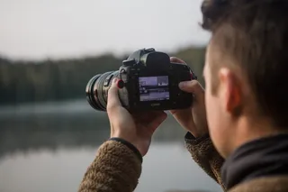 手持黑色单反相机的人