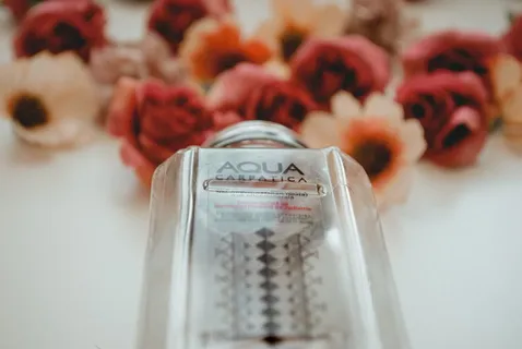 在白色表面上的花附近的 Aqua Carpatica 瓶