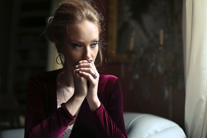 一位身穿红色天鹅绒连衣裙的金发女郎坐在白色沙发上