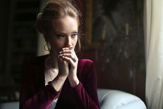 一位身穿红色天鹅绒连衣裙的金发女郎坐在白色沙发上