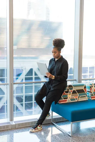 穿着黑色夹克的女人站在蓝色沙发旁