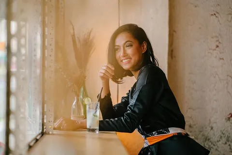 坐在吧台椅子上靠近透明酒杯的女人