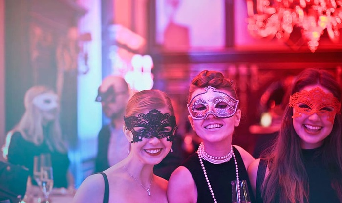 三名戴着口罩的年轻女子在夜总会里拿着酒杯摆姿势