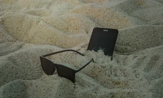 沙滩上的手机和太阳镜照片