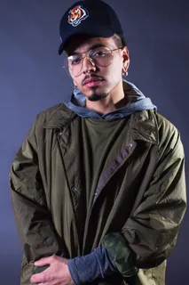 身穿橄榄绿黑领夹克的男子站在黑色背景前