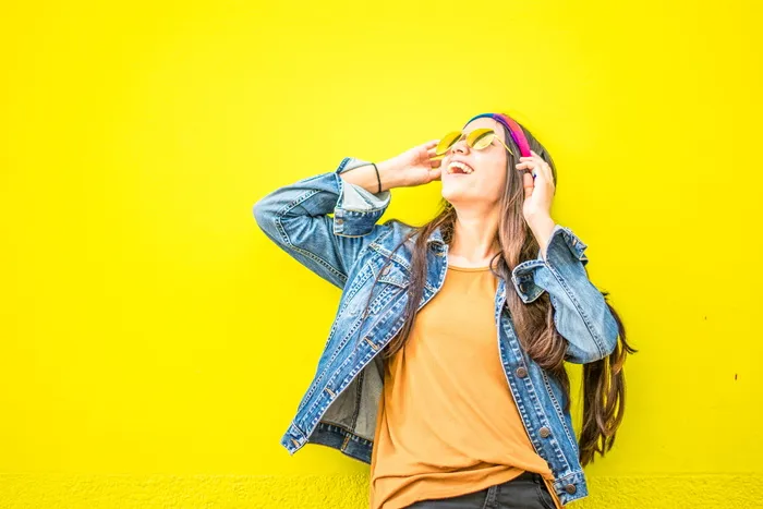 面带微笑的女人站在黄色的墙上，看起来笔直