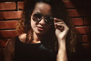 在墙上拿着太阳镜的女人