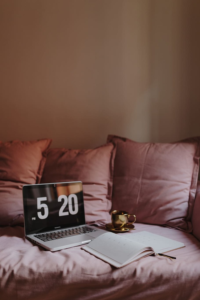 在粉色沙发上放着笔记本电脑的工作场所