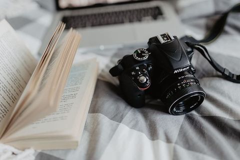 一台相机、MacBook和一本书在床上等着