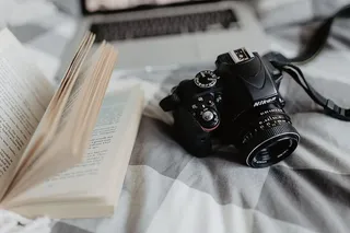 一台相机、MacBook和一本书在床上等着