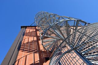 白天附着在混凝土建筑上的灰色螺旋楼梯的低角度摄影