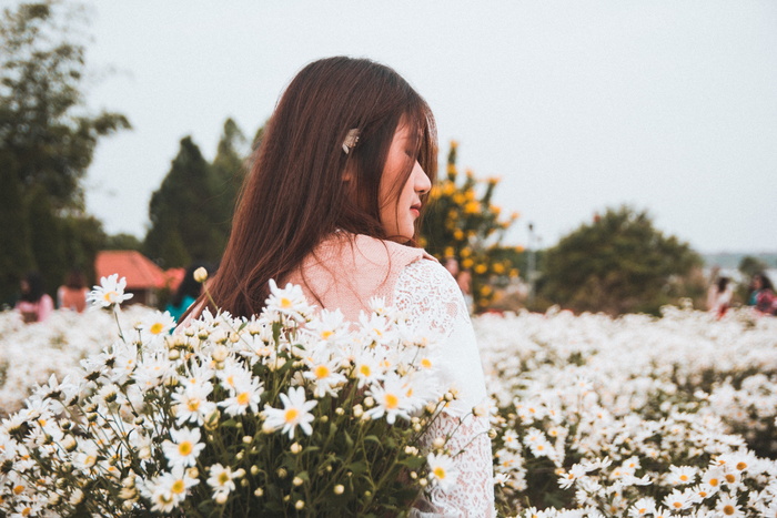 站在白色雏菊花边的女人