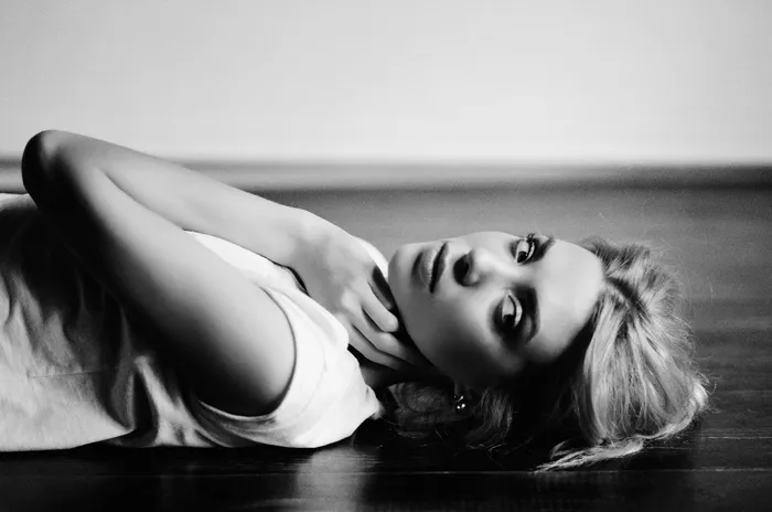 躺在拼花地板上的女人的灰度照片