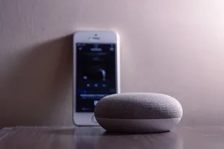 银色Iphone 5s旁边的灰色Google Home Mini