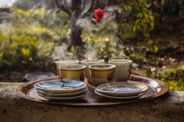 茶托旁边的棕色陶瓷茶杯放在棕色盘子上