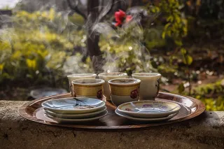 茶托旁边的棕色陶瓷茶杯放在棕色盘子上