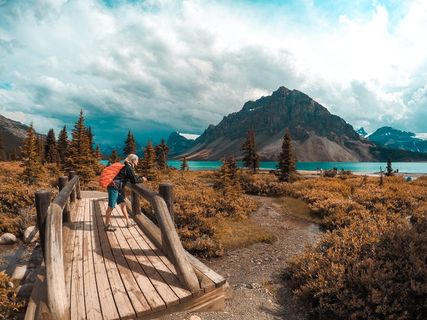 白天站在木桥上欣赏被水体包围的群山景色的人