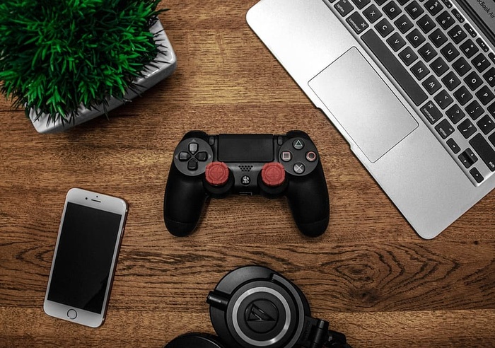 黑色索尼Ps4 Dualshock 4、银色Iphone 6旁边的银色Macbook，以及棕色木桌上的黑色圆形钥匙链