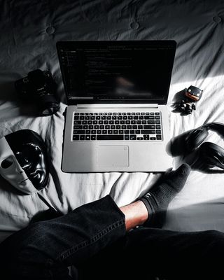 MacBook 位于床上的相机、运动相机、面罩和耳机中间