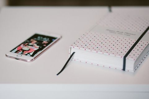 玫瑰金Iphone 6s旁边的白色和黑色波尔卡圆点书都在白色的木制桌子上 玫瑰金Iphone 6s旁边的白色和黑色波尔卡圆点书都在白色的木制桌子上