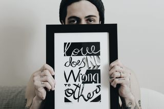 一个人拿着一个画框，里面写着“爱不会伤害别人”