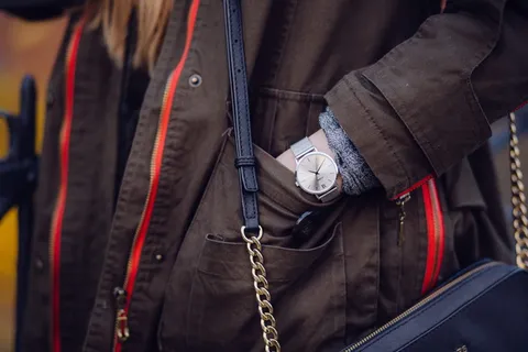 女人棕色外套,手放在口袋里,戴着银色模拟手表 女人棕色外套,手放在口袋里,戴着银色模拟手表