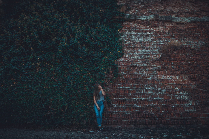 靠在褐色石墙上的女人