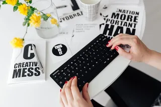 女性用手在远程无线电脑键盘上打字