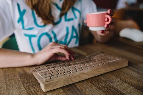 女性手在无线木质键盘上打字的特写