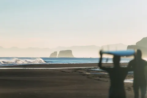 在海边附近拿着冲浪板的人的剪影 在海边附近拿着冲浪板的人的剪影