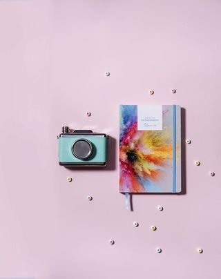 青色，银色milc相机，旁边，油漆粉爆裂书，封面，粉色，表面，灰色