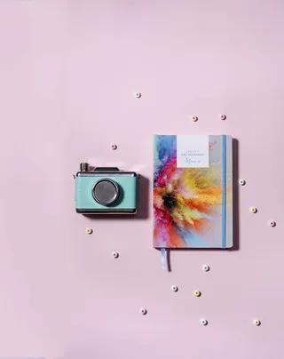 青色，银色milc相机，旁边，油漆粉爆裂书，封面，粉色，表面，灰色