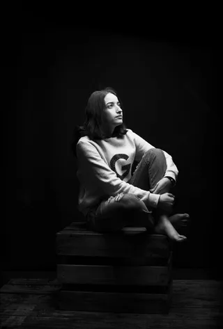 坐在木箱上的女人的灰度照片