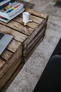 设计师设计的起居室室内有一张木箱桌、紫色沙发和灰色地毯