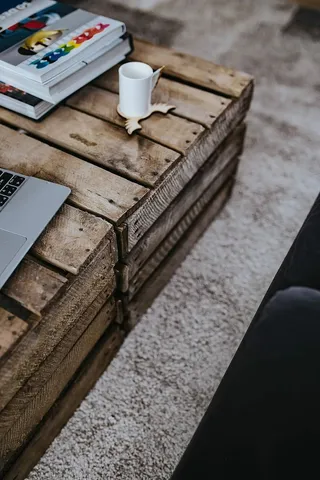 设计师设计的起居室室内有一张木箱桌、紫色沙发和灰色地毯